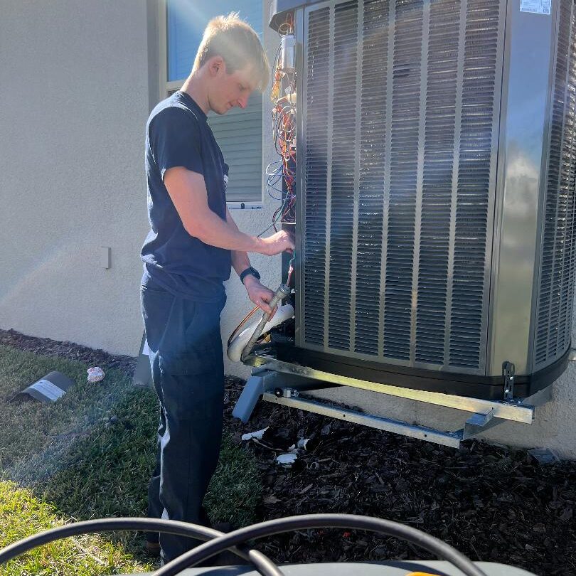 A man is cleaning the outside of an air conditioner.